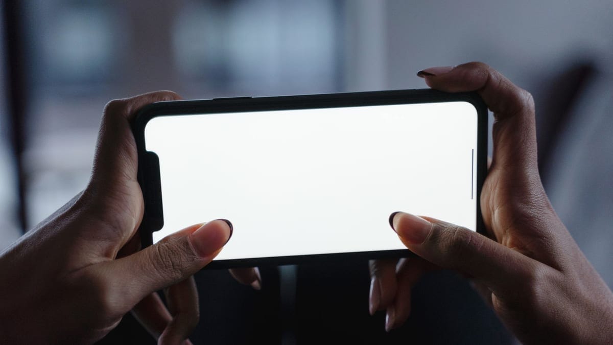 Close-up view of hands holding a smartphone with a blank white screen, perfect for mockup designs.
