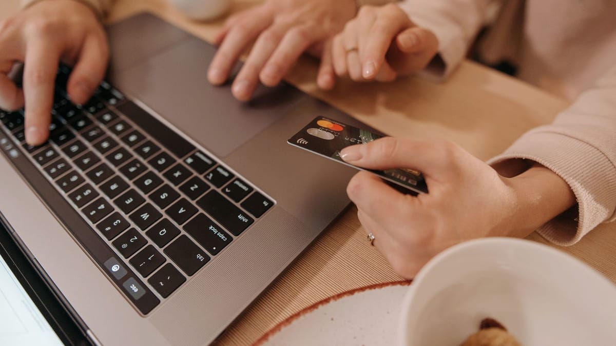 Close-up of hands using a laptop and credit card for an online payment or shopping transaction.