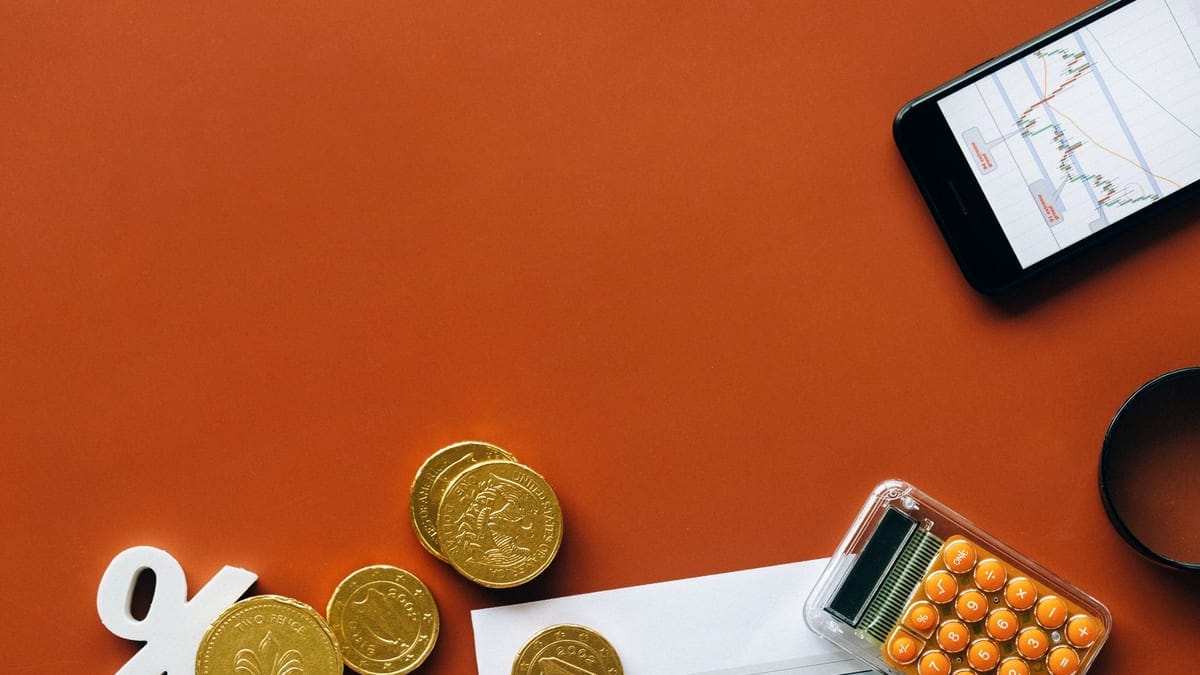 Flat lay showing coins, calculator, and charts on a red background for financial analysis and business concepts.