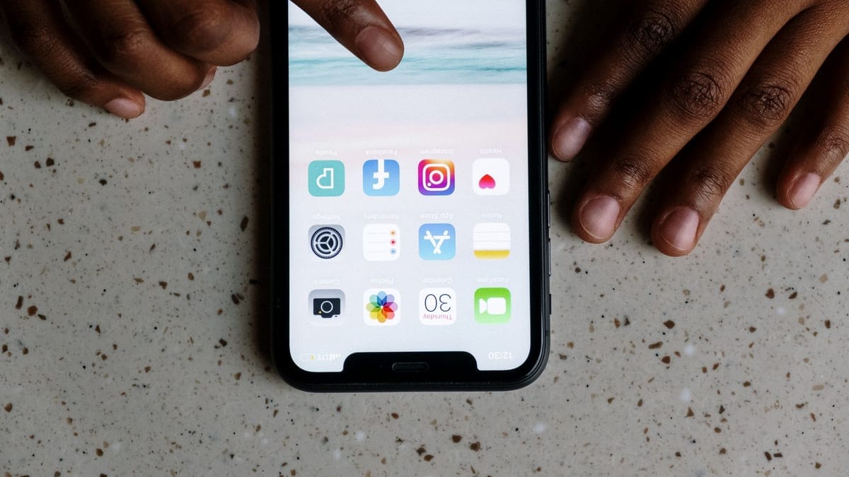 Close-up view of hands interacting with social media apps on a smartphone screen.