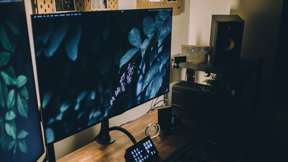 A stylish workspace setup featuring dual monitors, ambient lighting, and a wooden desk.