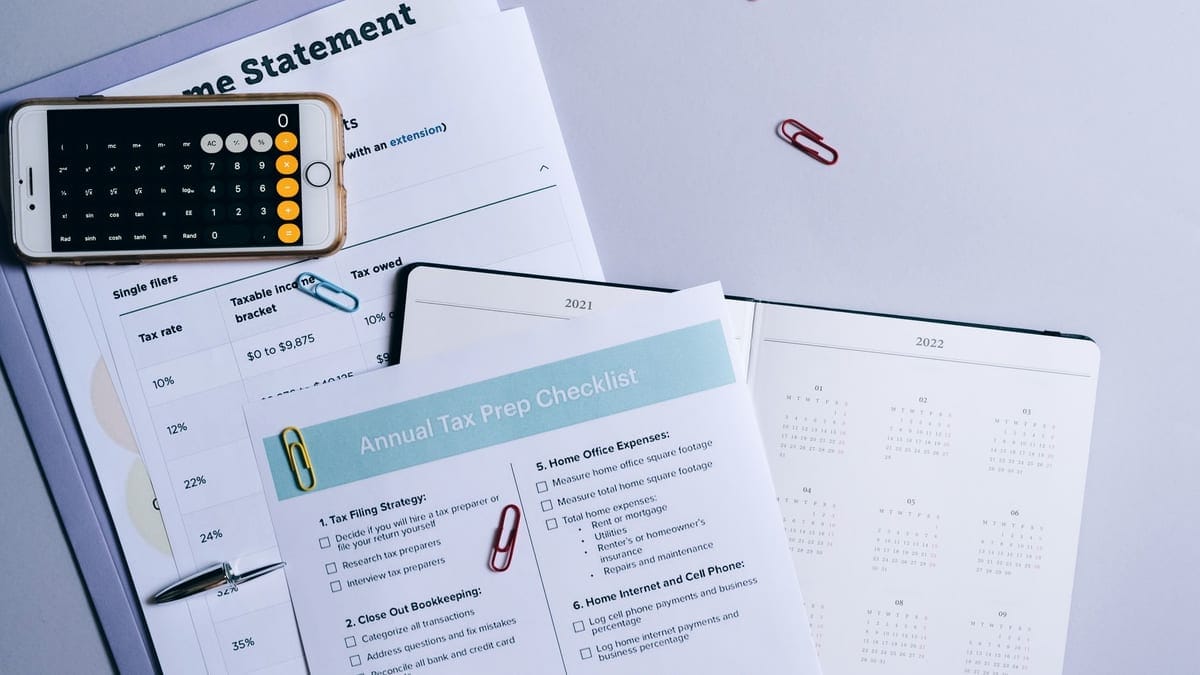 Flat lay of a tax preparation checklist, calculator, and financial documents on a desk.
